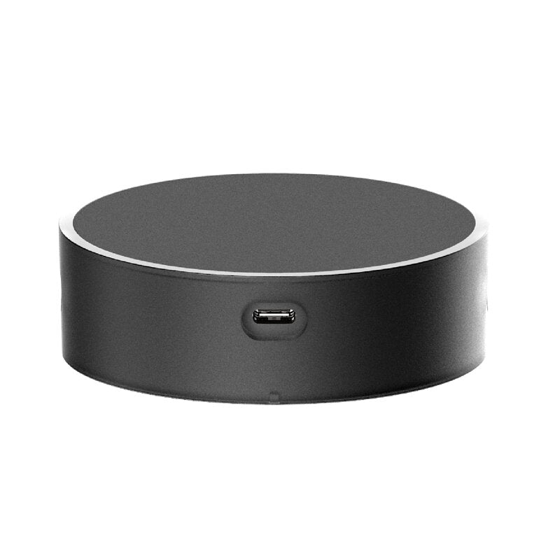 Round black electronic device with USB port on a white background
